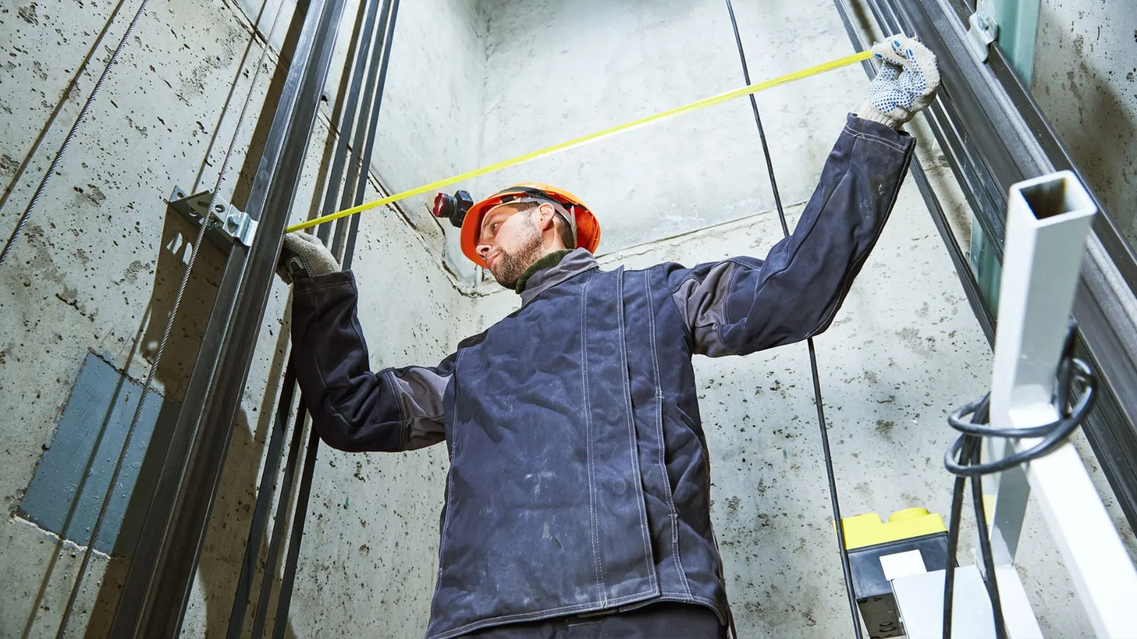Technician measuring an elevator shaft with a tape measure